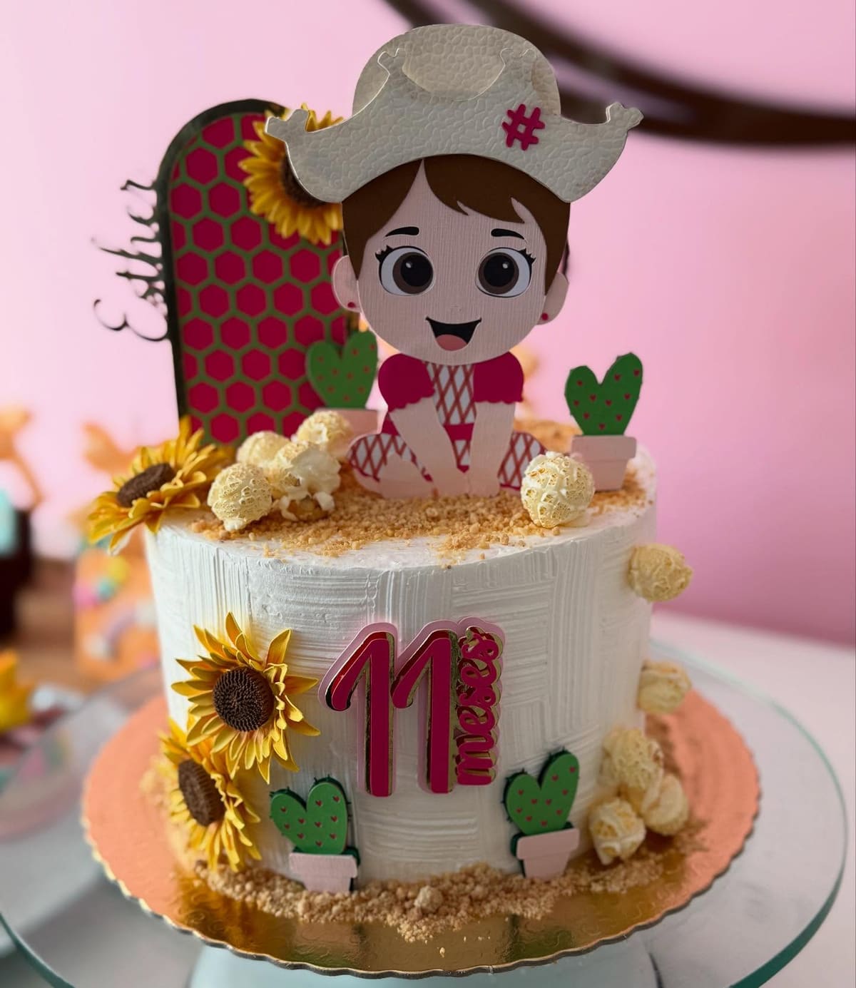Bolo de aniversário com girassóis e boneca confeiteira modelada no topo